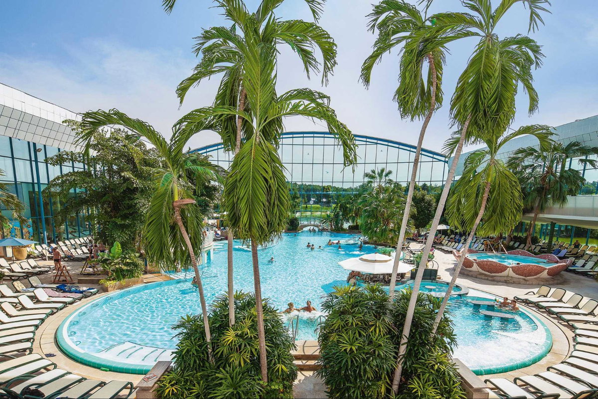 Therme Bad Wörishofen in Bayern: Großes Becken mit Palmen und Liegenstühlen und geöffnetem Cabriodach