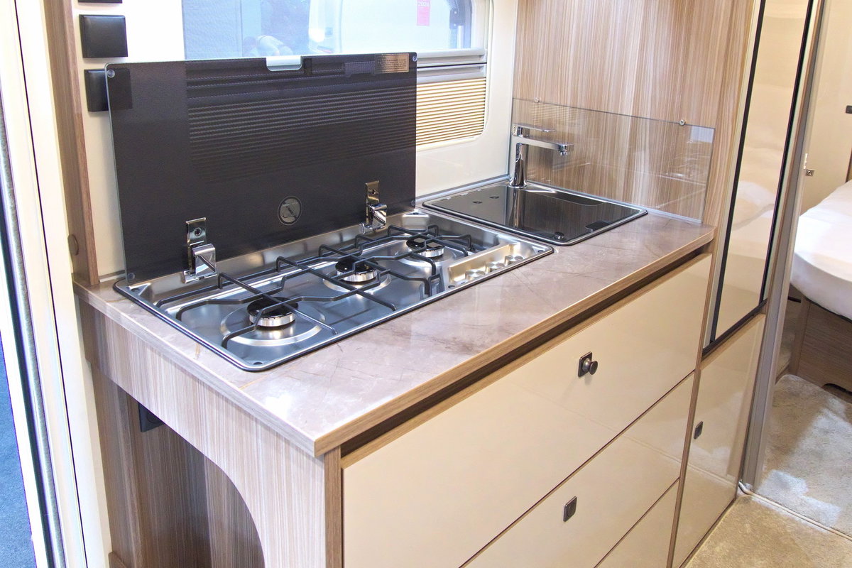 Fendt Tendenza 560 SFDW na Caravan Salon 2026: zabudowa kuchenna z 3-palnikową kuchenką, zlewem, lodówką i schowkiem.