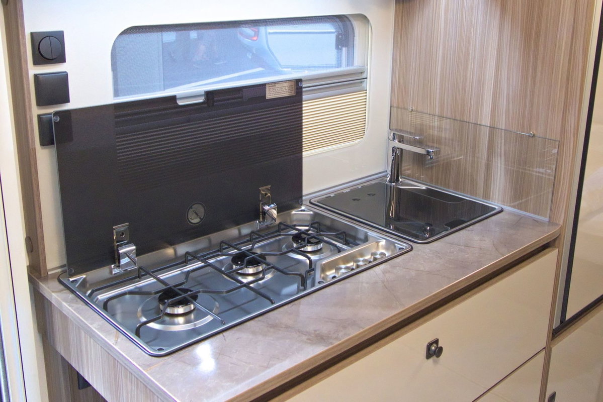 Fendt Tendenza 560 SFDW na Caravan Salon 2026: zabudowa kuchenna z 3-palnikową kuchenką i zlewem.